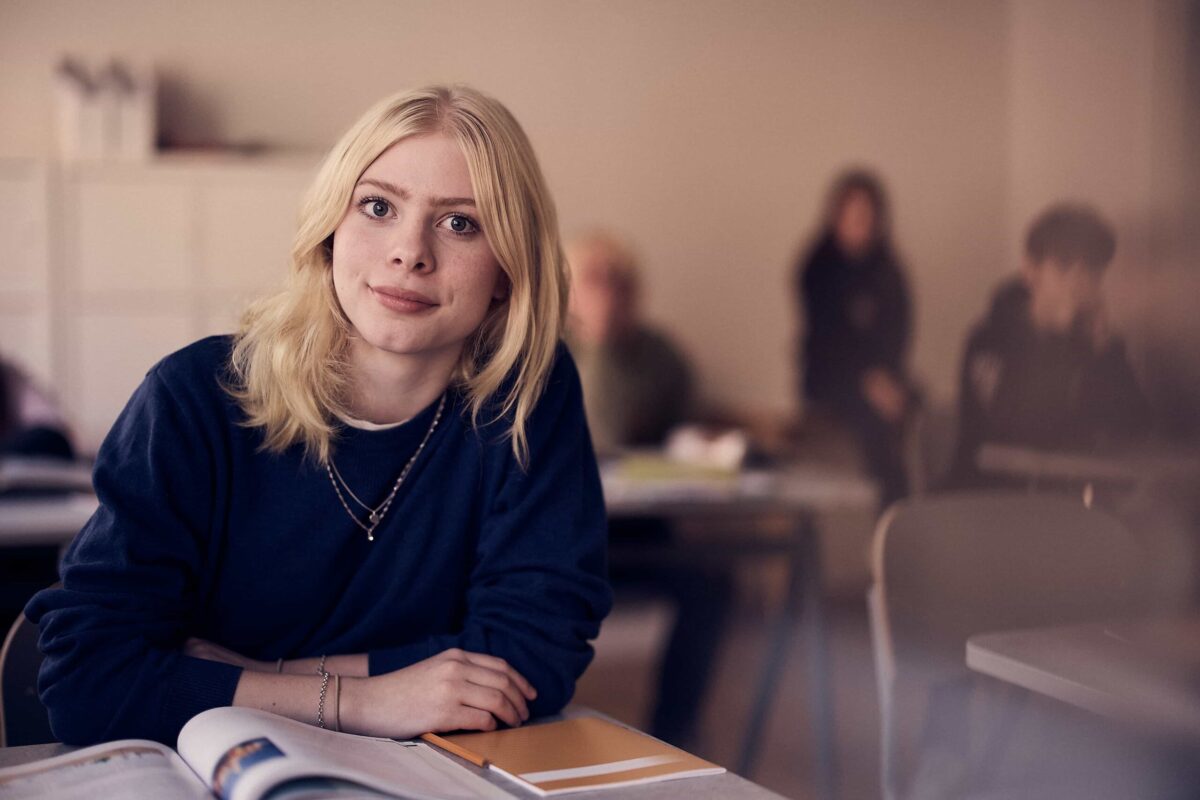 Elev på Snitz Grundskola sitter i ett klassrum med en lärobok på bänken framför sig.